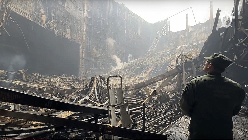 In this grab taken from video released by Investigative Committee of Russia on Saturday, March 23, 2024, an investigators from the Investigative Committee of Russia examines the burned concert hall after an attack on the building of the Crocus City Hall on the western edge of Moscow, Russia. (Investigative Committee of Russia via AP)