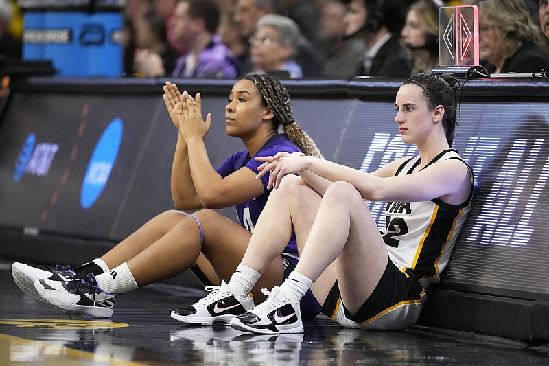 Holy Cross guard Simone Foreman and Iowa guard Caitlin Clark wait to check into Saturday's first-round women's NCAA Tournament game in Iowa City, Iowa. (Associated Press)