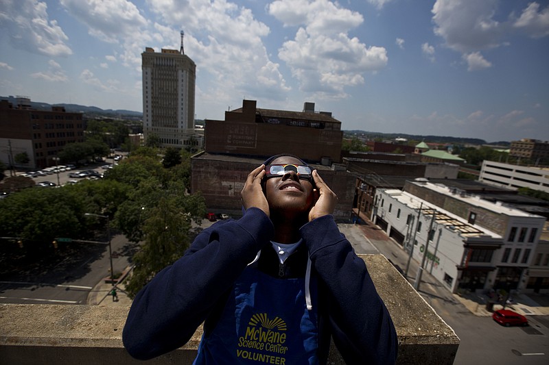 FILE - Justin Coleman, of Birmingham, Ala., holds his glasses up to his eyes as he watches the solar eclipse atop a parking structure, Monday, Aug. 21, 2017, in Birmingham. Safe solar eclipse glasses block out the sun’s ultraviolet rays and nearly all visible light. When worn indoors, only very bright lights should be faintly visible – not household furniture or wallpaper. (AP Photo/Brynn Anderson, File)