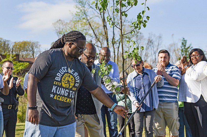 Nicholas Norfolk (front left) and John Payne, vice president and president of the Walnut Valley Homeowner's Association Inc., plant a tree at Walnut Valley Neighborhood Park in Little Rock on Saturday, March 30, 2024 in remembrance of the EF3 tornado that tore through their neighborhood last year. Among those in attendance at the event was Little Rock Mayor Frank Scott Jr. (behind the tree). (Arkansas Democrat-Gazette/Staci Vandagriff)