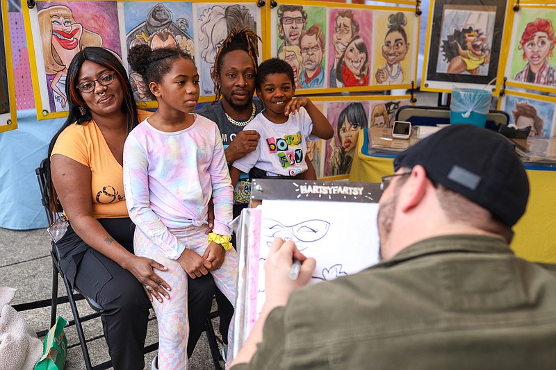 Staff photo by Olivia Ross / From left, Dominique, Faith, Terrance and Neo Cummings sit to have their caricature drawn by Dennis Hart at the Chattanooga River Market on March 9. The market will be from 10 a.m.-5 p.m. Saturday at the Tennessee Aquarium Plaza, featuring a variety of vendors, selling handmade art, crafts and food.