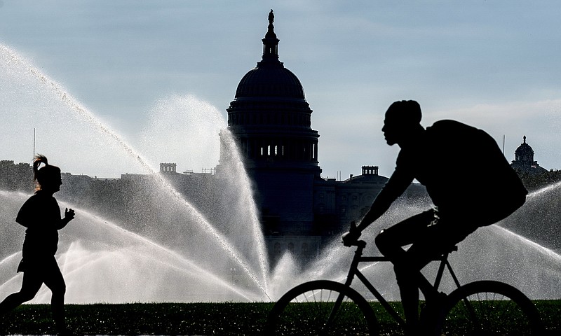 FILE - The Capitol is seen as water sprinklers soak the National Mall on a hot summer morning in Washington, July 15, 2022. A new poll finds that most Americans share many core values on what it means to be an American despite the country’s deep political polarization. The poll from The Associated Press-NORC Center for Public Affairs Research found that about 9 in 10 U.S. adults say the right to vote, the right to equal protection under the law and the right to privacy are important or very important to the U.S.’s identity as a nation.(AP Photo/J. Scott Applewhite)