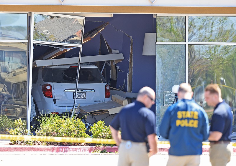 Law enforcement officers investigate a crime scene at the Massage Envy store in the Lewis Crossing Shopping Center in Conway where a vehicle crashed through into the business Saturday, April 6, 2024. (Arkansas Democrat-Gazette/Colin Murphey)