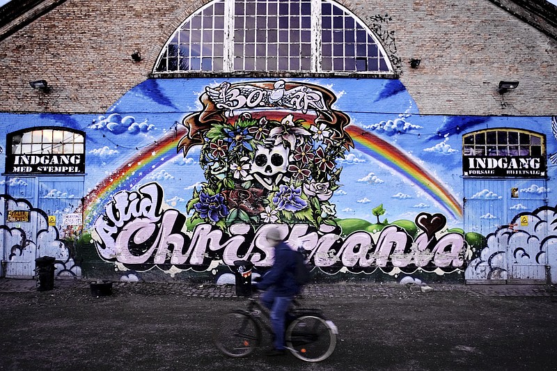 FILE - A man rides his bike passing by The Grey Hall at Christiania neighborhood of Copenhagen, Feb. 11, 2004. The aging hippies who more than 50 years ago squatted a derelict naval base in Copenhagen and turned it into freewheeling Christiania neighborhood, want to boot out criminals controlling the community's lucrative hashish market for good, by ripping open the paved street on Saturday, April 6, 2024, where small brown lumps openly change hands and which has been a thorn in side of many. (Peter Hove Olesen/Polfoto via AP, File)