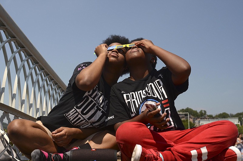 Staff Photo by Robin Rudd / From left, Kenya Williams and her cousin, Kamau Mealing, both of Chattanooga, share their eclipse glasses in the last second of totality during the August 2017 eclipse. Chattanooga will experience another solar eclipse Monday but will not be in the path of totality.