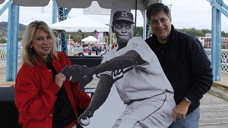 Staff file photo / Janna Jahn, left, and Warren Dropkin pose with a cardboard cutout of former Chattanooga Lookouts pitcher Satchel Paige at the Engel Stadium booth on the Walnut Street Bridge during the Wine over Water festival in October 2012.