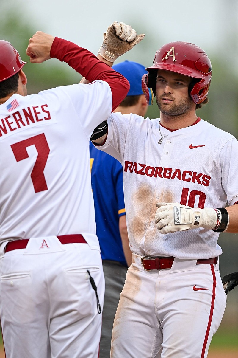 Arkansas second baseman Peyton Stovall (right) receives congratulations from first base coach Bobby Wernes on Wednesday after hitting a single during the sixth inning of the top-ranked Razorbacks’ 8-2 victory over San Jose State at Baum-Walker Stadium in Fayetteville. Stovall went 4 for 4 with 2 RBI in the victory. More photos at arkansasonline.com/411uabaseball/.
(NWA Democrat-Gazette/Caleb Grieger)