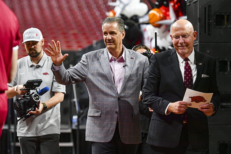 Arkansas men’s basketball Coach John Calipari (middle) waves as he walks off the stage Wednesday with broadcaster Chuck Barrett (right) following Calipari’s introductory news conference at Walton Arena in Fayetteville. The Razorbacks have no returning scholarship players or newcomers for Calipari to inherit, but Athletic Director Hunter Yurachek didn’t sound anxious about the new coach’s ability to build a roster for next season. “I’m really confident that he can put a great team together pretty quickly,” Yurachek said.
(NWA Democrat-Gazette/Hank Layton)