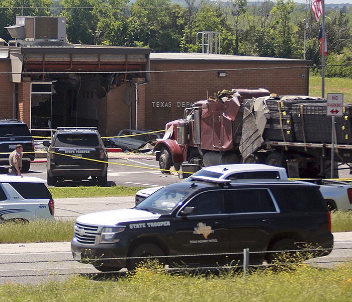 Emergency personnel work at the scene after an 18-wheeler crashed into the Texas Department of Public Safety office in Brenham, Texas, on Friday. A suspect is in custody in connection with the commercial vehicle’s crash at the office in the rural town west of Houston. Texas DPS officials say multiple injuries were reported in the crash.
(AP/Lekan Oyekanmi)