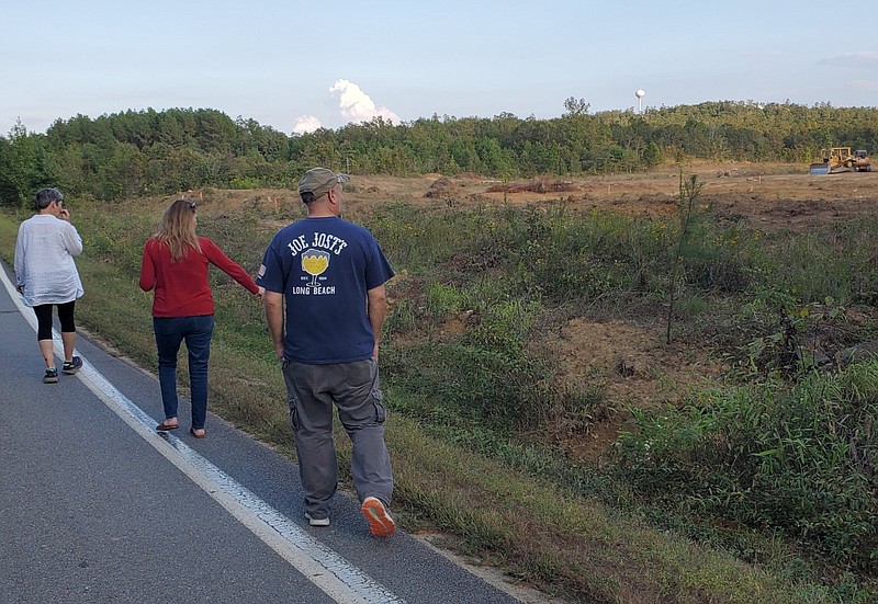 Meredith Hawkins (center), the secretary of the Pinnacle Mountain Community Coalition, walks with coalition President Chris Centofante and her boyfriend, Matt Sprenger, near the area planned to become the Paradise Valley Subdivision in this September 2021 file photo. The area shares a boundary with Hawkins' land. (Arkansas Democrat-Gazette file photo)
