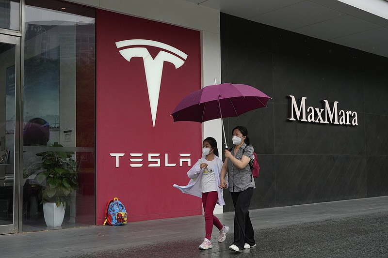 Residents walk past a Tesla showroom in Beijing in May 2023.
(AP)
