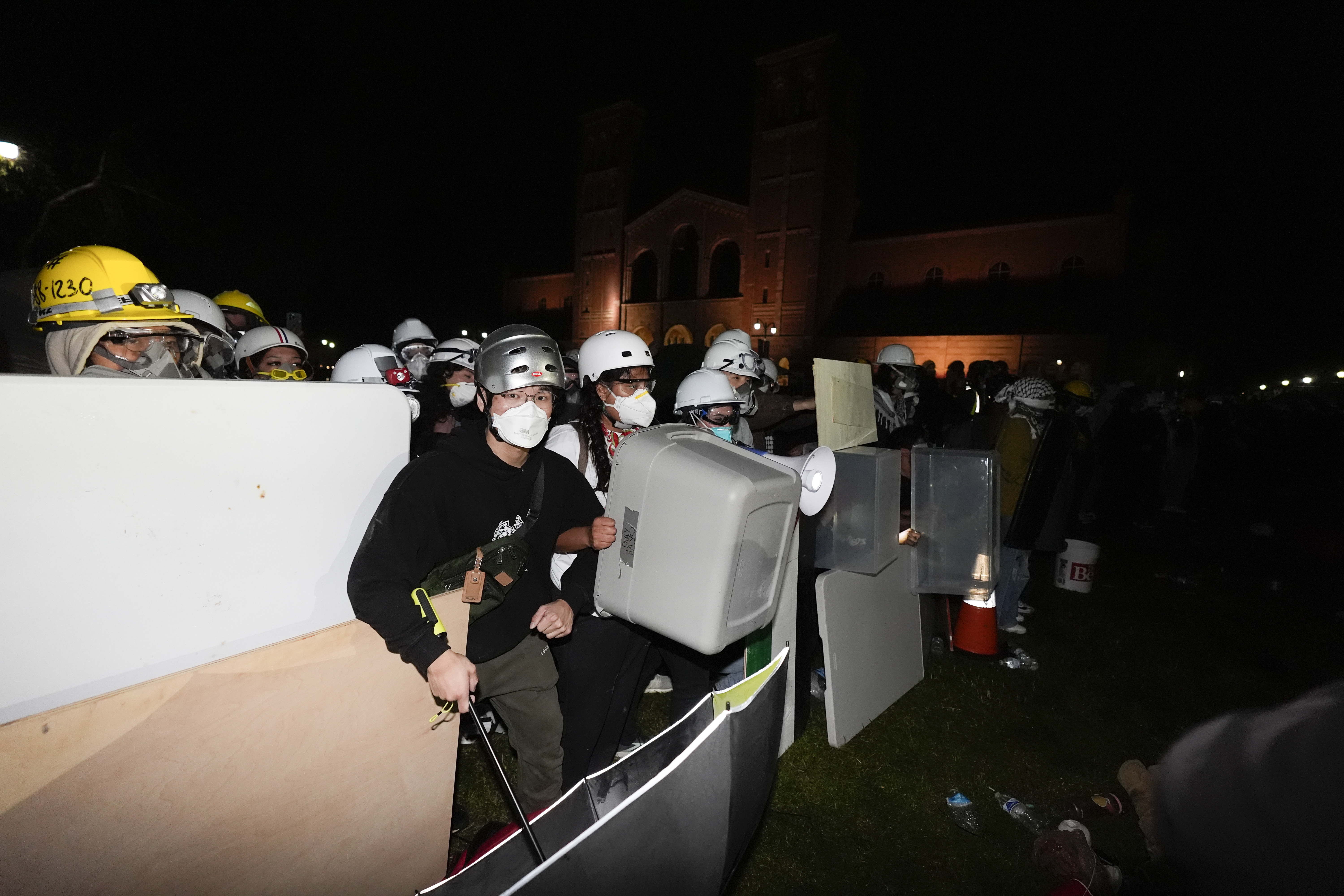 Pro-Palestinian demonstrators use makeshift shields as police advance on them on the UCLA campus Thursday, May 2, 2024, in Los Angeles. (AP Photo/Ryan Sun)