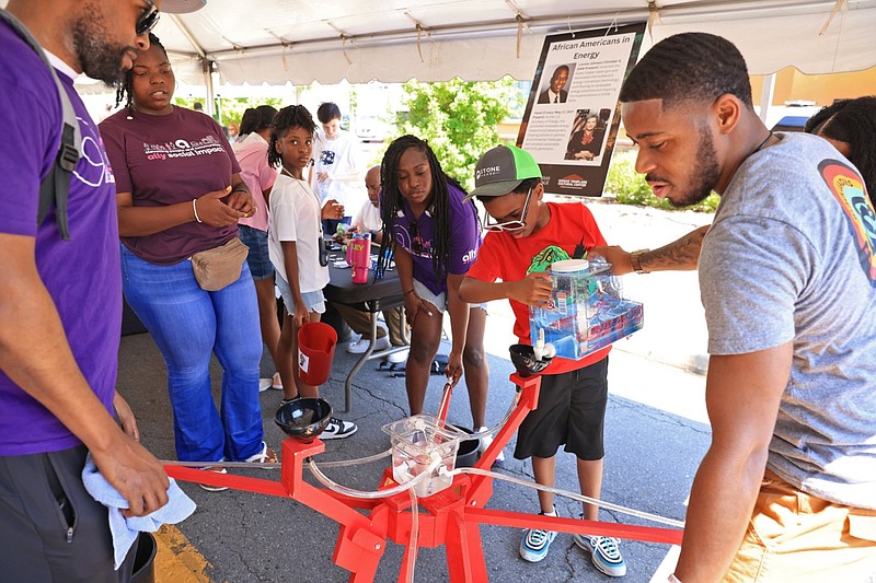 Visitors in downtown Little Rock work with an interactive exhibit on hydroelectricity hosted by the Museum of Discovery during the Juneteenth Arkansas Festival on Saturday, June 15, 2024. (Arkansas Democrat-Gazette/Colin Murphey)