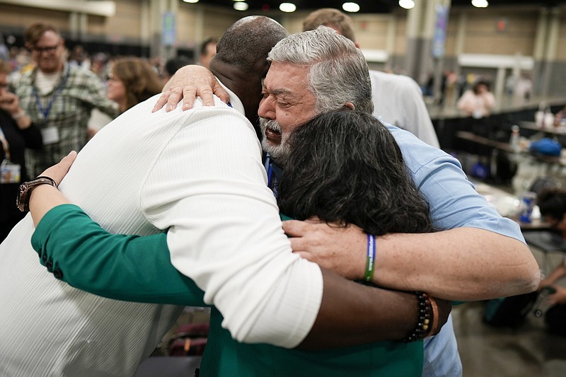 United Methodists hug at the church's general conference in Charlotte, N.C. The denomination lifted its bans on the ordination of self-avowed practicing homosexuals and prohibitions on same-sex marriages.