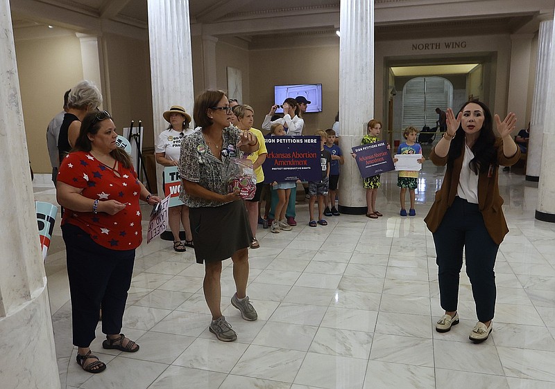 Jaime Land (right) with the Arkansas secretary of state’s office tells people where they can stand in order to keep walking lanes open before petitions are brought into the state Capitol on Friday, July 5, 2024. Proponents and opponents of a proposed constitutional amendment on abortion were on hand Friday as the group attempting to overturn the Arkansas law banning nearly all abortions said it had enough signatures for its proposal to make the November 2024 ballot. (Arkansas Democrat-Gazette/Thomas Metthe)