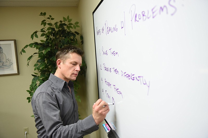 Brian O’Gary of Lightwell Therapy, a mental health clinic in North Little Rock, writes on a whiteboard in his office on Wednesday, July 3, 2024. (Arkansas Democrat-Gazette/Staci Vandagriff)