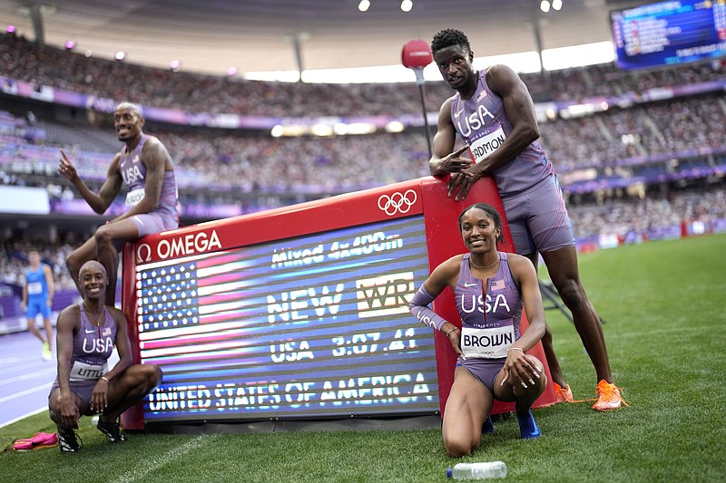 University of Arkansas freshman Kaylyn Brown (bottom right) poses with her teammates — including Razorbacks volunteer coach Shamier Little (bottom left) — after setting a world record of 3 minutes, 7.41 seconds in the 1,600-meter mixed relay on Friday at the Paris Olympics. Brown ran 49.45 seconds on the final leg and helped to break the previous world mark of 3:08.80 set last year.
(AP/Bernat Armangue)