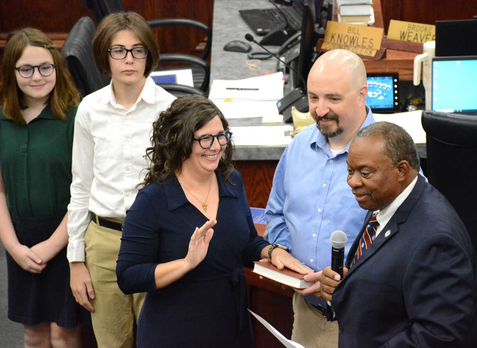 Staff Photo by Robin Rudd / Tennessee State Representative Yusuf Hakeem, right, speaks before administering the oath of office to Jill Black. Black was joined by children, Clara and Levi, and husband Matt. The six members of the Hamilton County school board who were elected in August were sworn in and administered their Oaths of Office on September 4, 2024. The members were Steve Slater, Ben Daugherty, Jackie Anderson-Thomas, Jodi Schaffer, Felice Hadden and Jill Black.