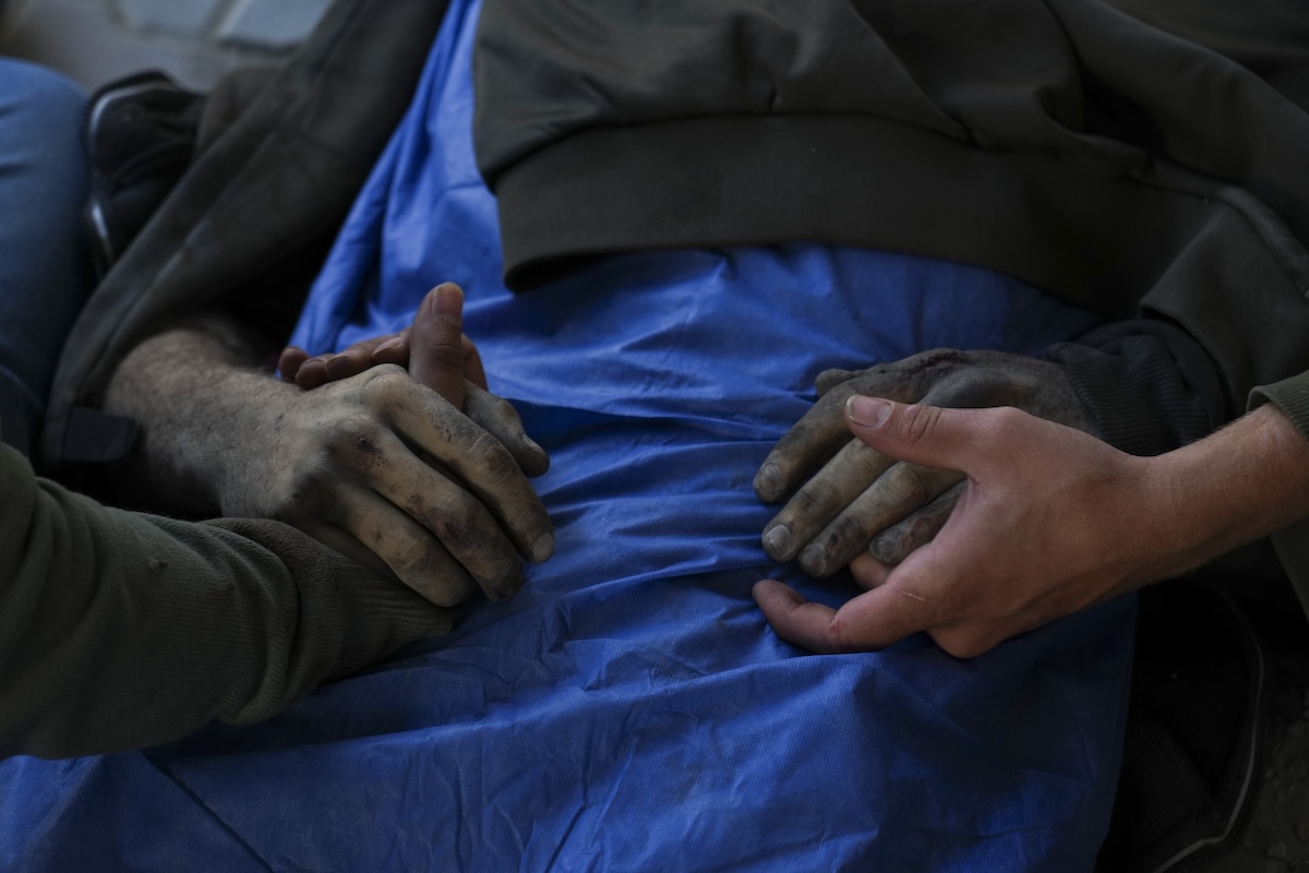EDS NOTE: GRAPHIC CONTENT - Palestinians hold the hands of their relative who was killed in an Israeli army airstrike, at Shifa Hospital in Gaza City, Tuesday, March 18, 2025. (AP Photo/Abdel Karem Hanna)