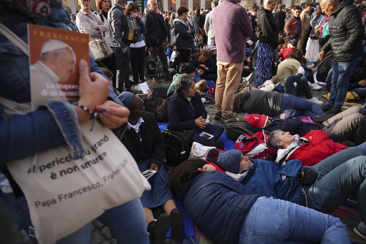 Faithful rest on the ground outside St Peter's Basilica waiting for the funeral of Pope Francis in St. Peter's Square at the Vatican, Saturday, April 26, 2025. (AP Photo/Andrew Medichini)