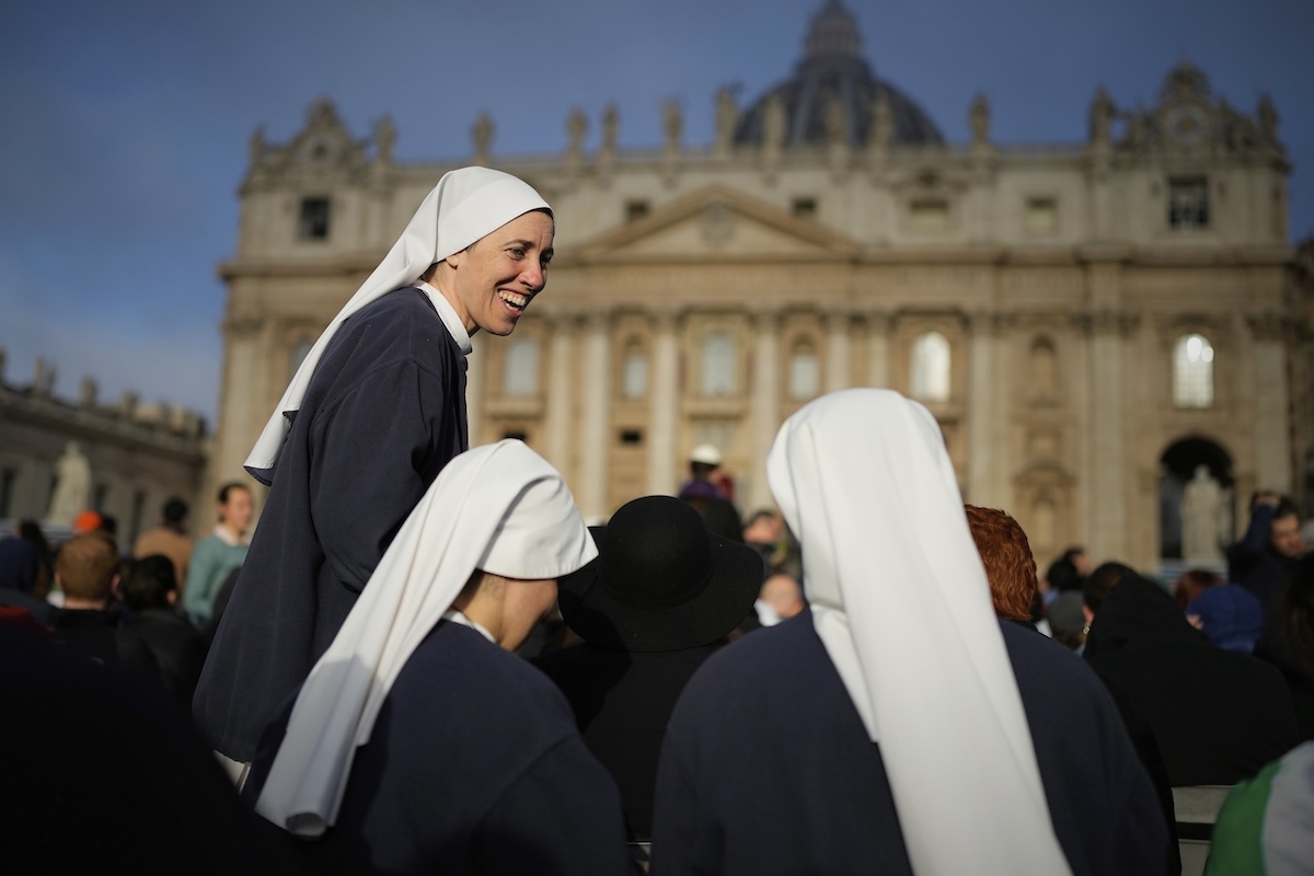 Nuns share a laugh as people gather for the funeral of Pope Francis in St. Peter's Square at the Vatican, Saturday, April 26, 2025. (AP Photo/Andreea Alexandru)
