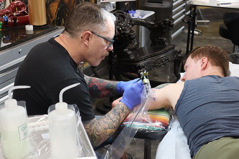 Artist Josh Henderson (left) tattoos a stylized video game character on Austin Mauney’s (right) arm at Black Cobra on May 28, 2025. (Arkansas Democrat-Gazette/Jesse Cain)