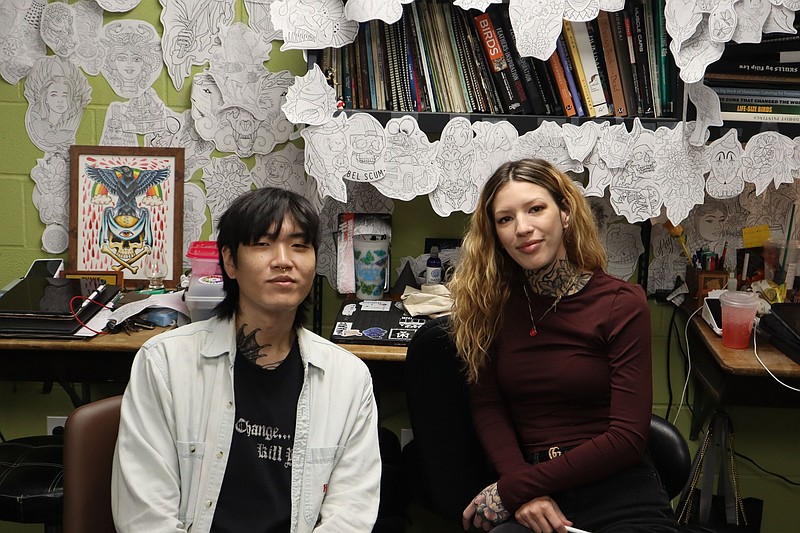 Tattoo artists Paul Lee (left) and Maia Brouillette (right) pose for a picture in the drawing studio at Black Cobra on May 28, 2025. (Arkansas Democrat-Gazette/Jesse Cain)