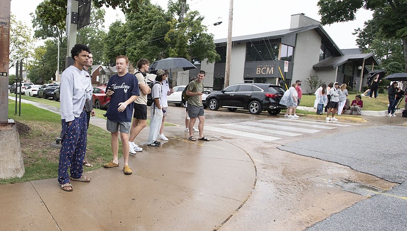 Members of the University of Arkansas community stand on the sidewalk while in Fayetteville Monday Aug. 25, 2025 after reports of an active shooter near Mullins Library. Visit nwaonline.com/photo for today's photo gallery. (NWA Democrat-Gazette/J.T. Wampler) .