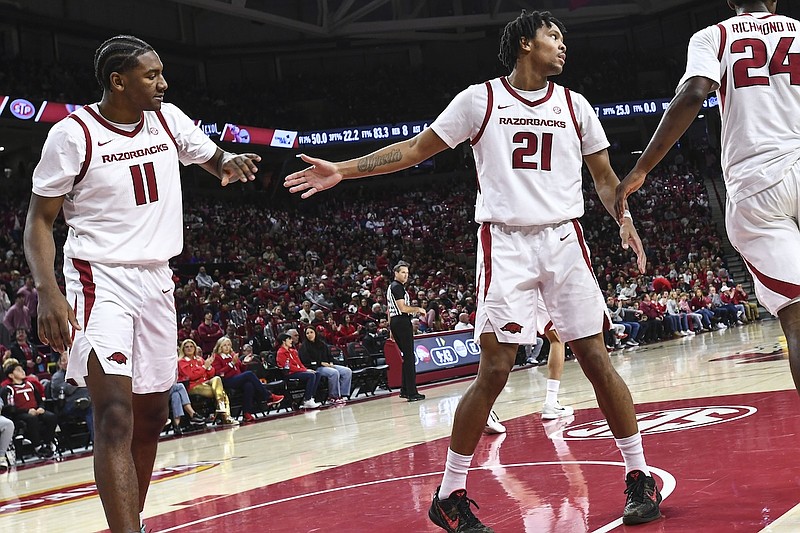 Arkansas Razorbacks players celebrating a basket against Mississippi State Bulldogs in a packed arena during an SEC basketball game.