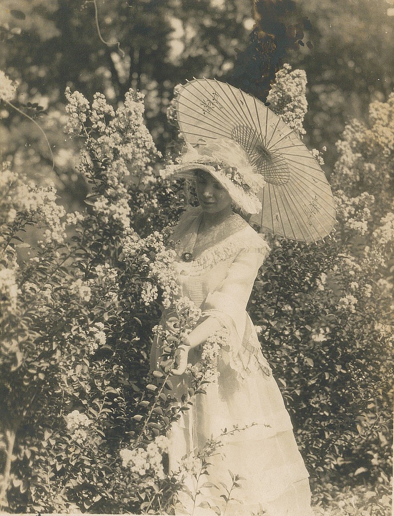 Vera Key poses in her home garden in Rogers about 1920 wearing a fashionable dress with matching hat and holding a hand-painted paper parasol. Some of Key's accoutrements are part of a new exhibit at the Rogers Historical Museum titled “Fashion Accessories: Adornments through History,” on show through Aug. 1.
(Courtesy Photo)