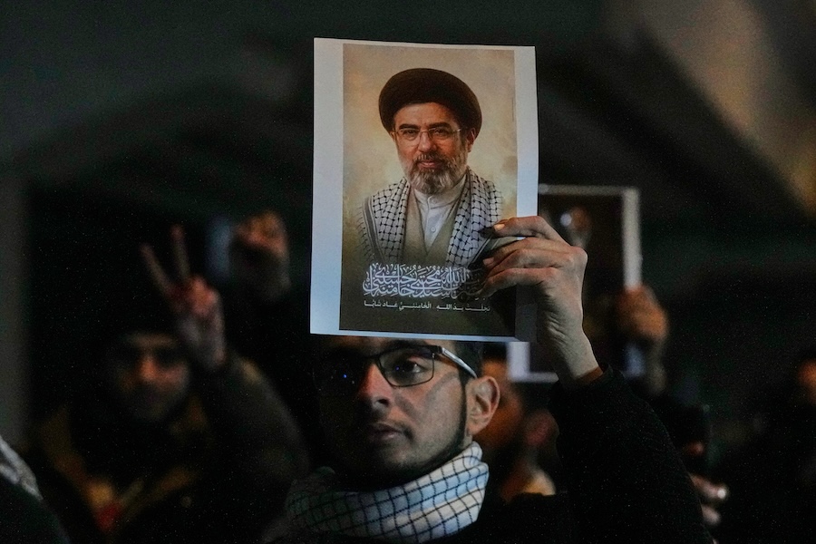 Iraqis hold a portrait of the new successor to Supreme Leader, Ayatollah Mojtaba Khamenei at a bridge leading to the fortified Green Zone where the U.S. embassy is located in Baghdad, Iraq, Monday, March 9, 2026. (AP Photo/Hadi Mizban)