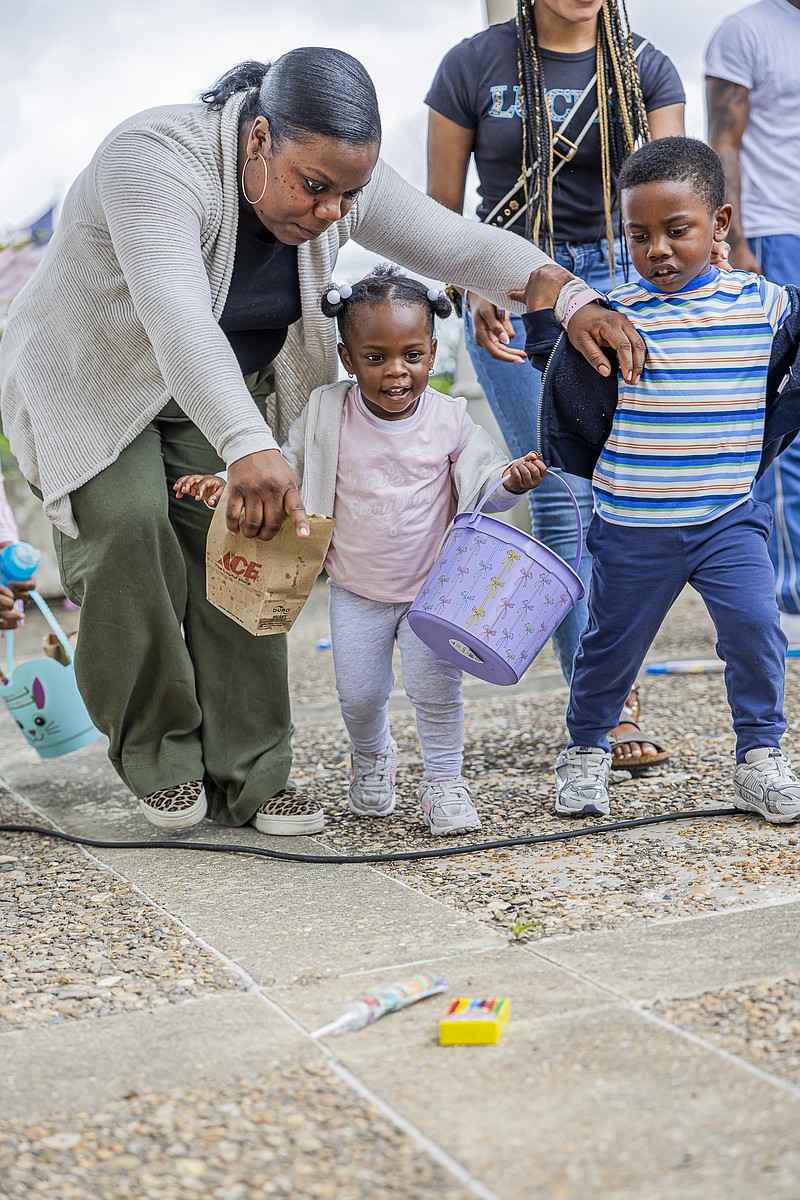 Kendria Barnes guides her 2-year-old daughter Garisyn as she carefully collects eggs, while her 4-year-old son, Garyn, looks on during the family-friendly hunt. (Pine Bluff Commercial/Eplunus Colvin)