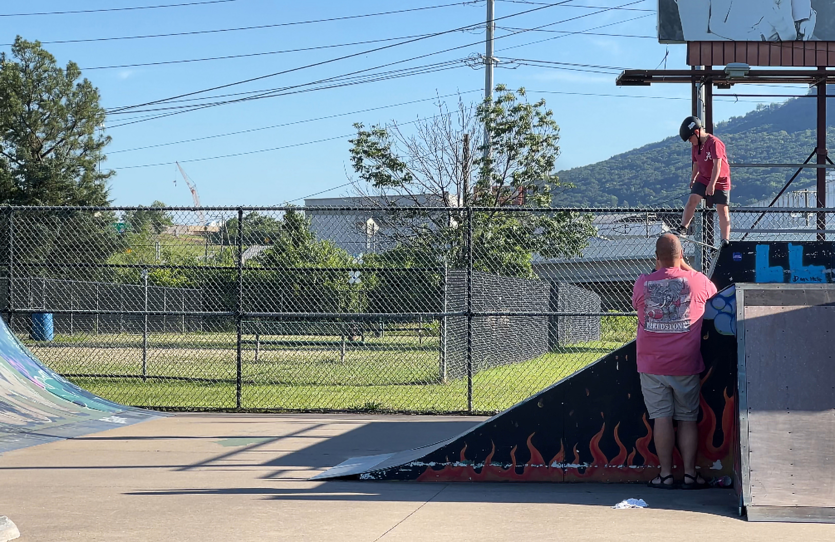 Staff photo by Cassandra Castillo / A father watches as his son skates down the ramp on May 21, 2025. The Chattanooga Skatepark renovation has been postponed for the second time, drawing concerns from the skater community.
