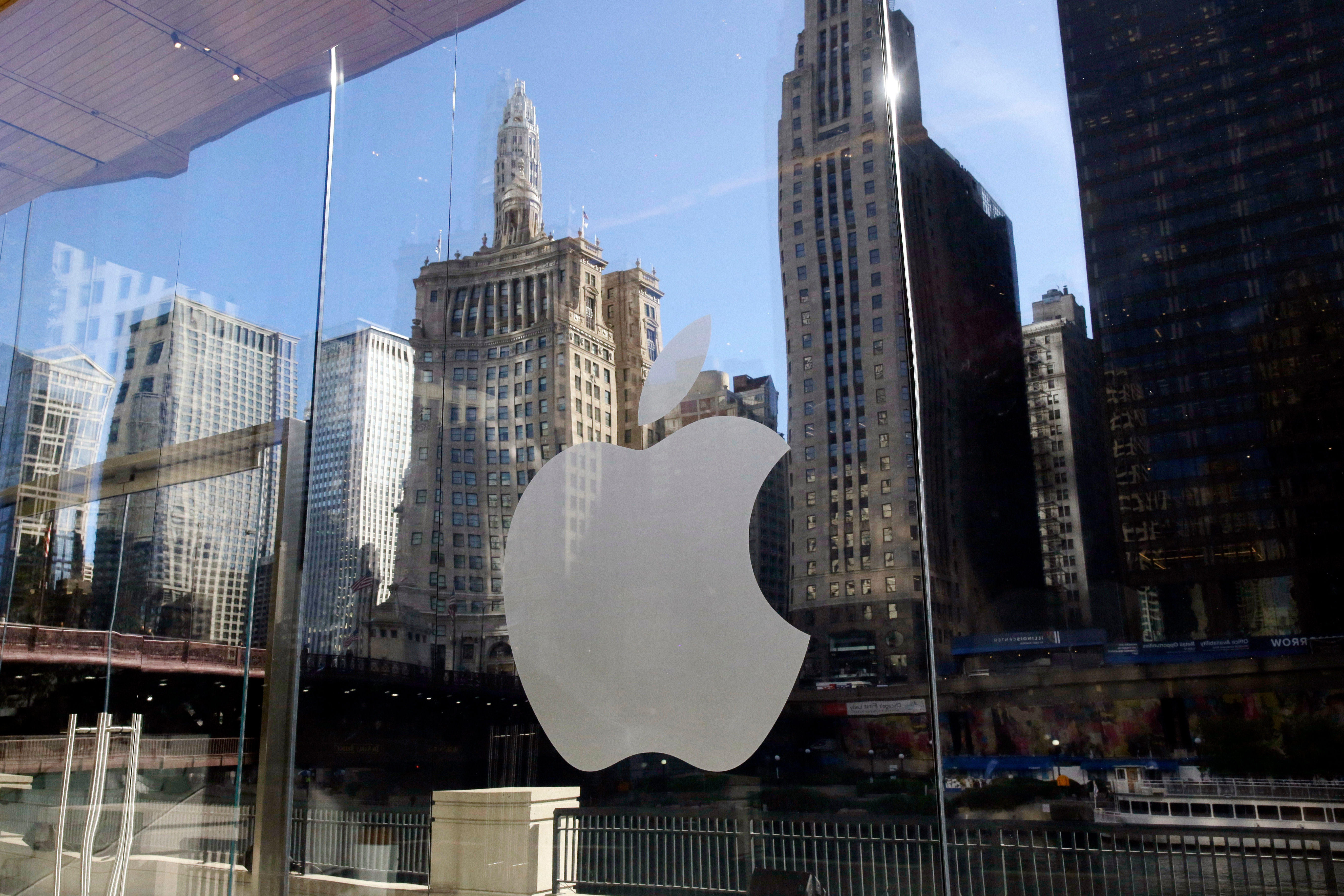 FILE - Buildings are reflected behind the logo at an Apple Store, in downtown Chicago, Oct. 19, 2017. (AP Photo/Kiichiro Sato, File)
