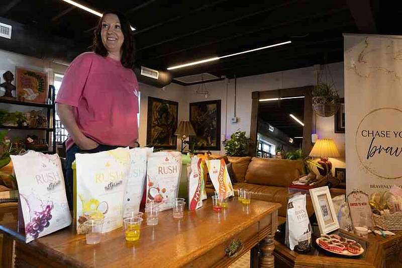 Sophie Ayers/News Tribune Courtney Huber of Bravenly stands by a table of sample products on Thursday during the She's Native Social.