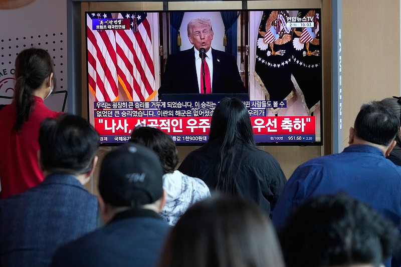 People watch a TV screen revealing a live broadcast of U.S. President Donald Trump's speech at the Seoul Railway Station in Seoul, South Korea, Thursday, April 2, 2026. (AP Photo/Ahn Young-joon)