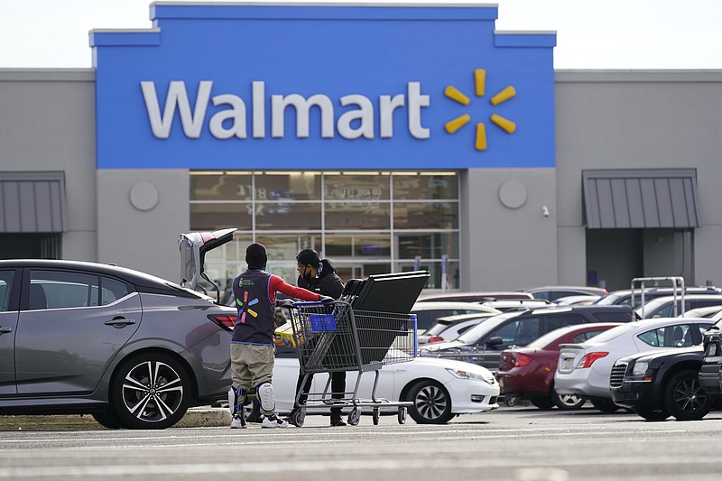 FILE - A Walmart employee helps a customer outside the Walmart store in Philadelphia, Wednesday, Nov. 17, 2021.  Walmart reported stronger sales for the fiscal first quarter, Tuesday, May 17, 2022,  but its profits took a beating as the nation’s largest retailer grappled with surging inflation on food and fuel and higher costs from a still snarled global supply chain.  (AP Photo/Matt Rourke, File)