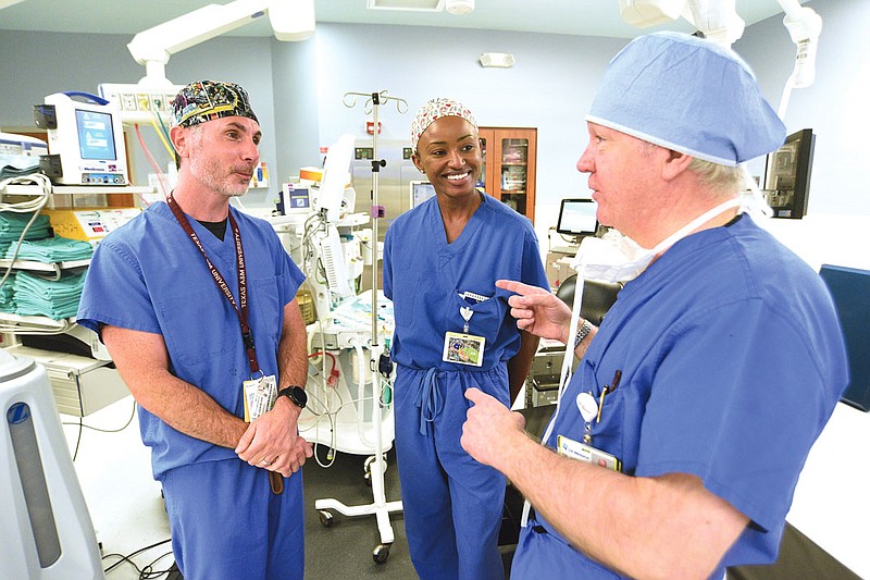 Staff photo by Matt Hamilton / From left, Dr. Sloan Youngblood, medical student Ngafla Bakayoko and Dr. Lee Jackson talk in a surgical theater at CHI Memorial Hospital in July.