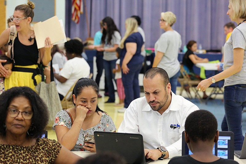 Staff photo by Erin O. Smith / Dorcas Gonzalez gets assistance registering her son for school from Dawin Aquino, an employee at EPB who was volunteering through La Paz, at East Lake Elementary Friday, August 3, 2018 in Chattanooga, Tennessee. Aquino, who said the program used to register students was difficult to navigate no matter what language parents speak, was helping Spanish-speaking parents get their children registered.  La Paz. is one of many local agencies benefited by support from the United Way.