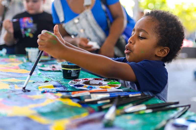 Staff photo by Olivia Ross  / Jaali Locklin paints on a group art piece. Hamilton County Schools celebrates the start of the 2022-23 school year with the 5th annual Back to School Bash at the First Horizon Pavilion on August 6, 2022. The event featured free school supplies, crafts, games, food, and information on community resources.