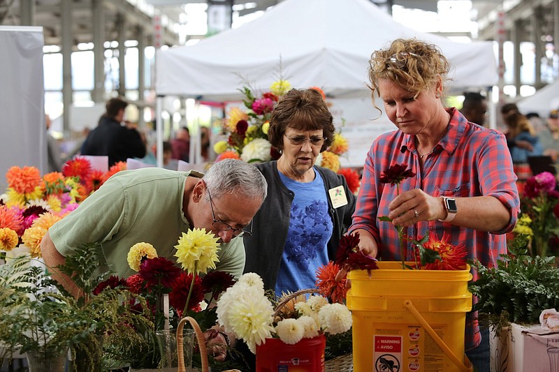 Staff file photo / Tony Russo, Dolores Ellis and Marcie Holt of the Tennessee Dahlia Society make flower arrangements during the Chattanooga Market Buskers Festival on Oct. 20, 2019. The organization will have a dahlia show Sept. 17-18 at the East Ridge Community Center.