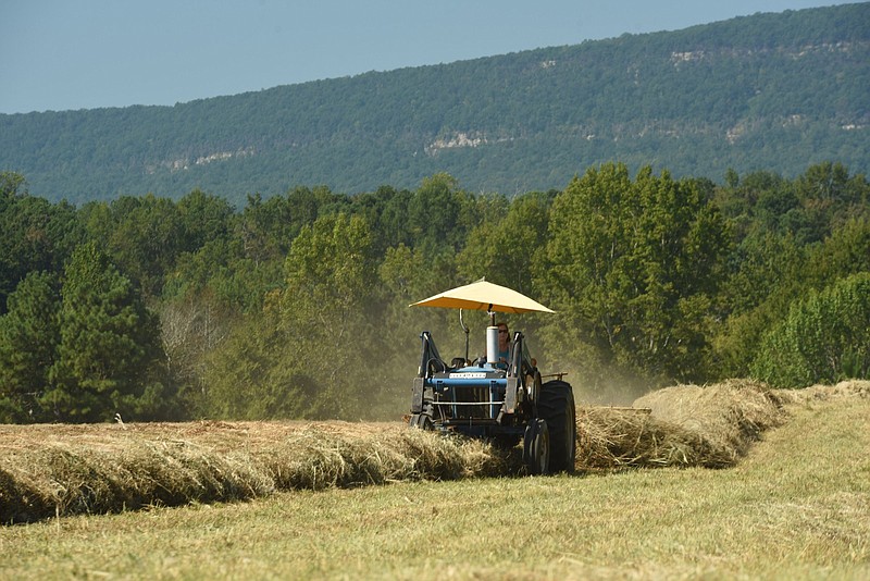 Staff file photo / Debbie Langston prepares hay for bailing by her husband, Jackie, on another tractor, in 2018 on the Frank Cagle farm in LaFayette, Ga.