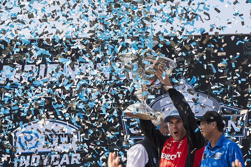 AP photo by Nic Coury / Team Penske driver Will Power holds up the IndyCar season championship trophy after finishing third in Sunday’s finale at Laguna Seca Raceway in Monterey, Calif.