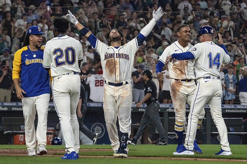 AP photo by Stephen Brashear / The Seattle Mariners' Eugenio Suarez, center, celebrates with Luis Castillo, left, Taylor Trammell (20), Julio Rodriguez, second from right, and third base coach Manny Acta after hitting a solo home run to beat the visiting Atlanta Braves on Sunday.