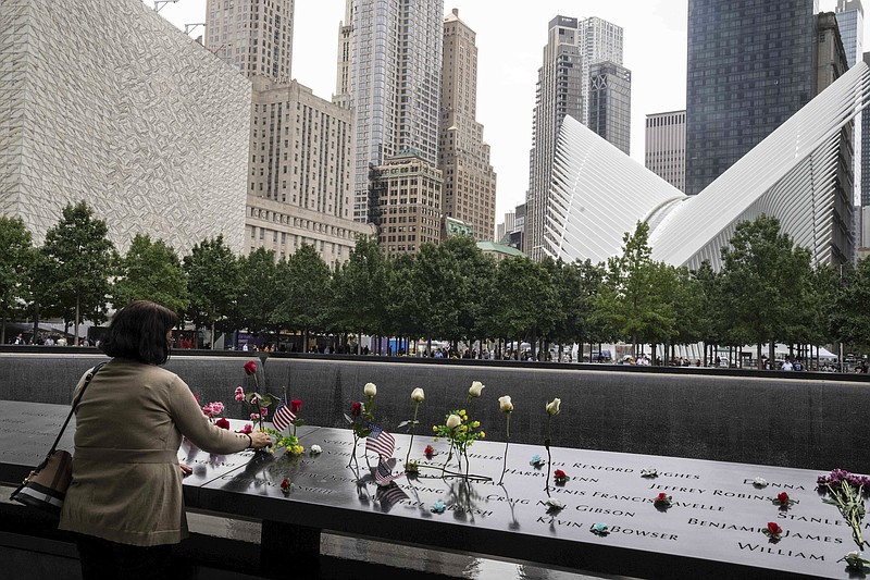 Photo by Desiree Rios / The New York Times / Maria Santiago places flowers on the name of her sister, Rosa Maria Feliciano, during the ceremony to commemorate the 21st anniversary of the Sept. 11 terrorist attacks, at the National September 11 Memorial and Museum in New York, on  Sept. 11, 2022.