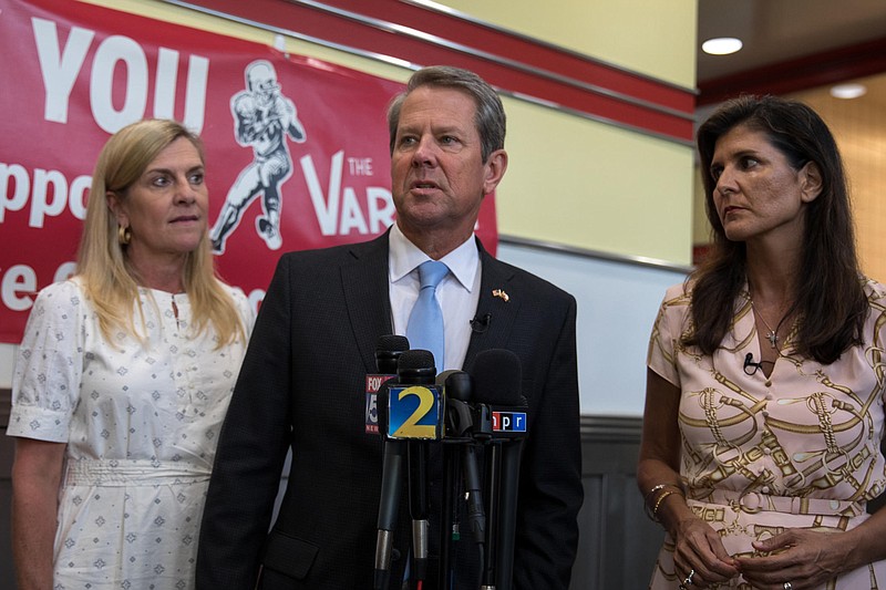 Georgia Public Broadcasting / Republican Gov. Brian Kemp takes questions during a campaign stop at The Varsity in Atlanta on Sept. 9, 2022, flanked by his wife, Marty Kemp (left), and former U.N. ambassador and South Carolina Gov. Nikki Haley.