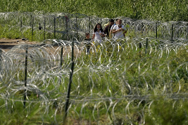 AP Photo/Eric Gay / Migrants walk along concertina wire toward Border Patrol officers after illegally crossing the Rio Grande River from Mexico into the U.S. at Eagle Pass, Texas, last month.