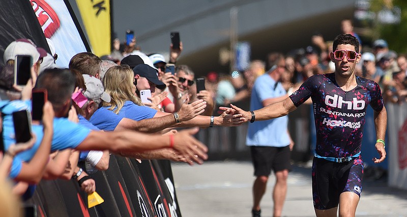 Staff Photo by Matt Hamilton / Joe Skipper high-fives fans as he wins the Ironman Chattanooga triathlon on Sunday, Sept. 26, 2021. About 2,000 athletes competed in the triathlon, which included swimming, bicycling and running competitions.