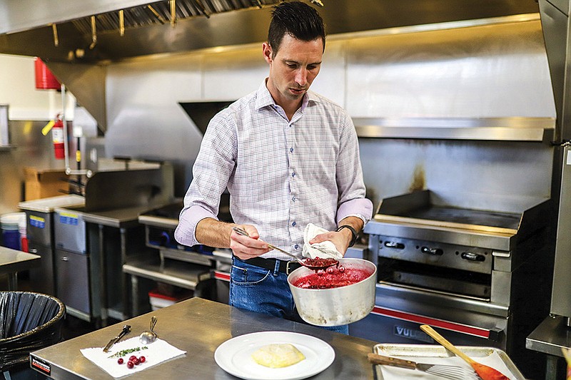 Staff photo by Olivia Ross / Shane Stone of High Haute Foods prepares a baked cheese with cranberry sauce.