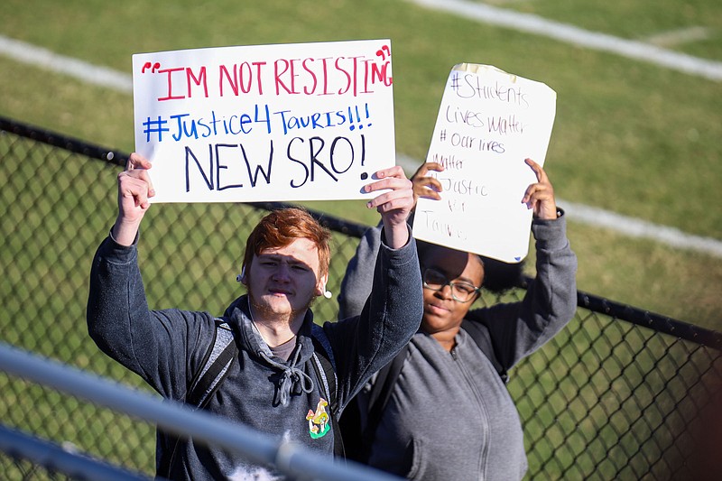 Staff photo by Olivia Ross  / East Ridge High School students walk a lap around the football field, many carrying signs and chanting Friday in protest of the forceful arrest of a student by the school's SRO.